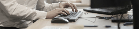 IT professional typing on a desktop keyboard at an office workstation