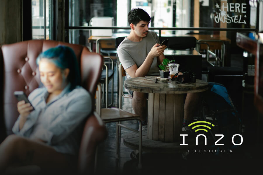 Two young people browse their phones in a public cafe setting
