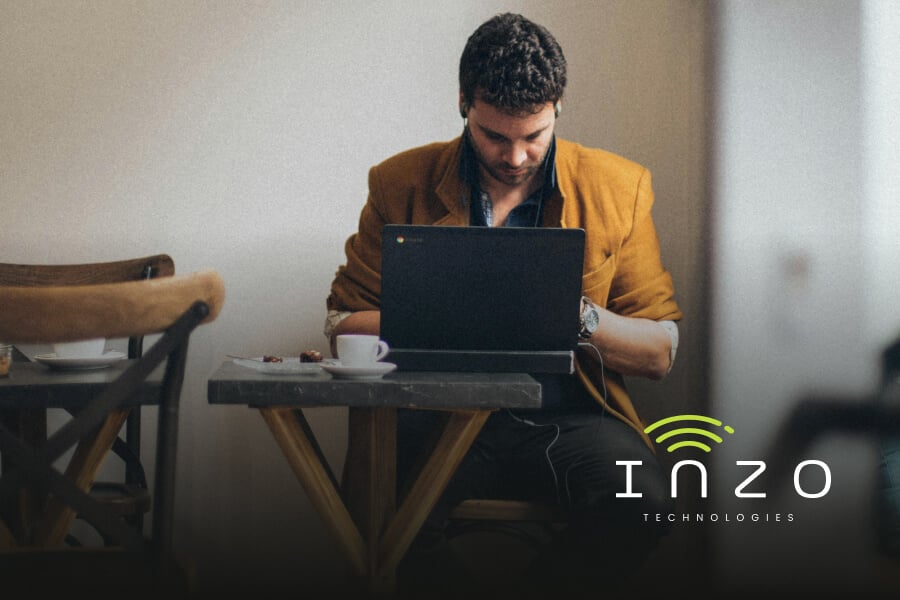 A man works on his laptop in a cafe setting.
