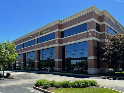 Exterior view of a three-story brick office building with reflective windows and 