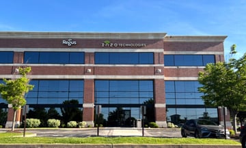 Front exterior view of the office building entrance area with Inzo Technologies signage above reflective windows.