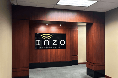 Office lobby entrance with dark wood paneling and a black wall sign reading “Inzo Technologies.”
