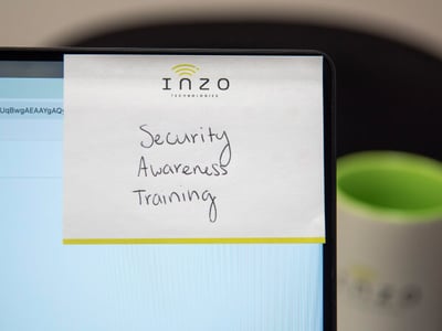 Inzo Technologies notepad with “Security Awareness Training” handwritten on it, attached to a computer monitor