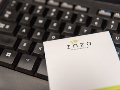 Close up of a computer keyboard with an Inzo Technologies branded sticky note pad