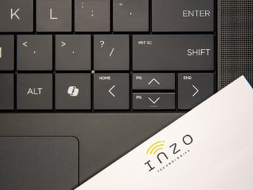 Close up of a laptop keyboard with an Inzo Technologies branded sticky note pad.
