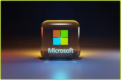 A glossy 3D Microsoft app icon with the four-color Windows logo and “Microsoft” text, lit dramatically against a dark blurred background.