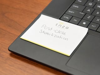 Close-up of an Inzo Technologies sticky note on a laptop reading “Post-close stabilization.”